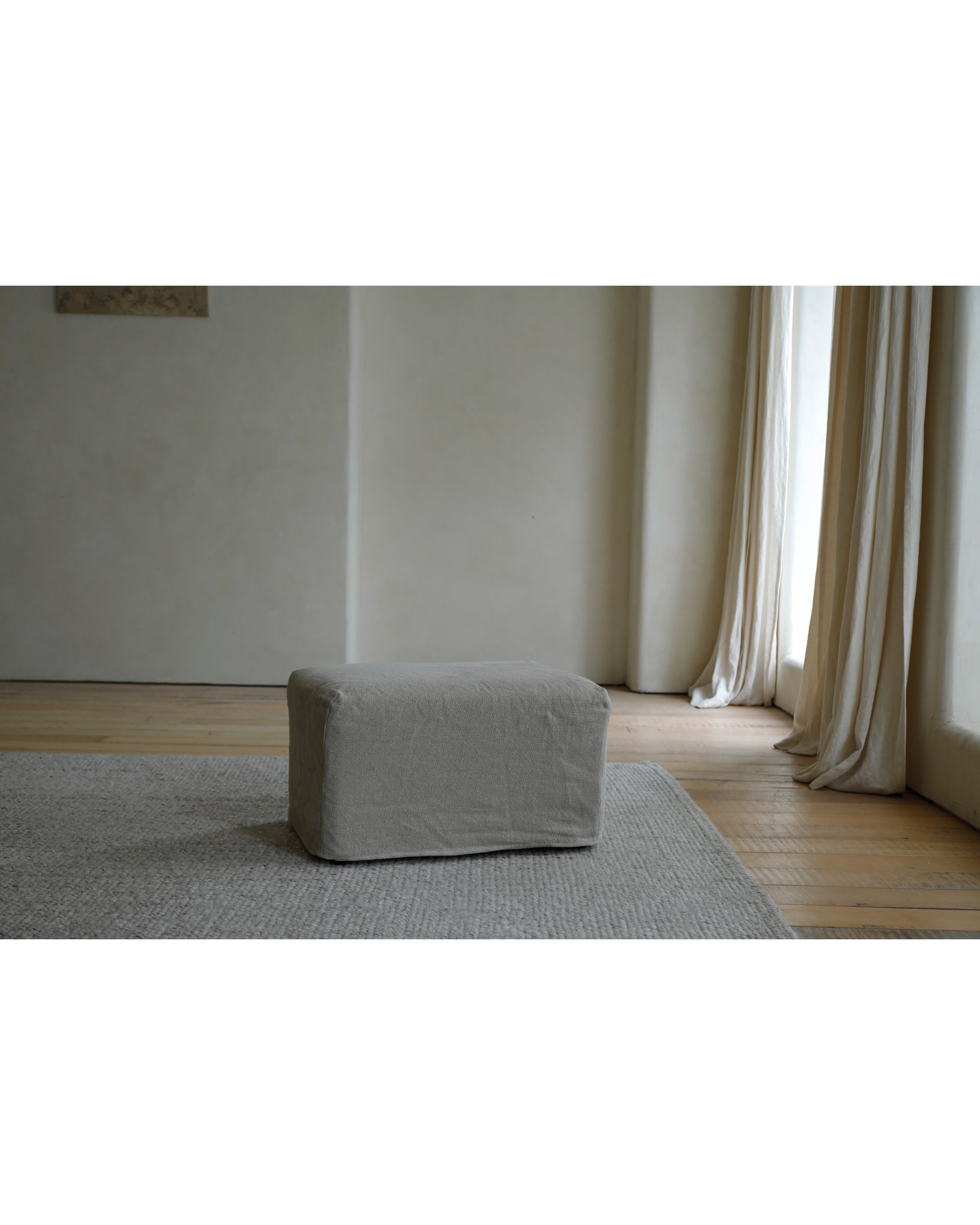 Eve Ottoman in Khaki linen fabric, styled on a rug.