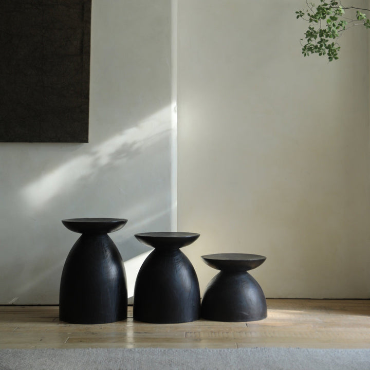 Black Sandglass Tables of different heights in a serene minimalist living room.
