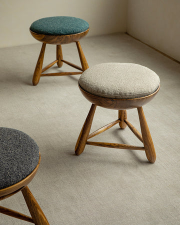 Mocho Stool in zebrawood with teal, light gray, and dark gray cushioned seats. Modern stool design.