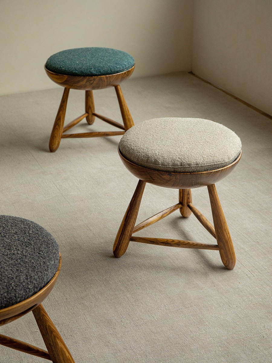 Mocho Stool in zebrawood with teal, light gray, and dark gray cushioned seats. Modern stool design.