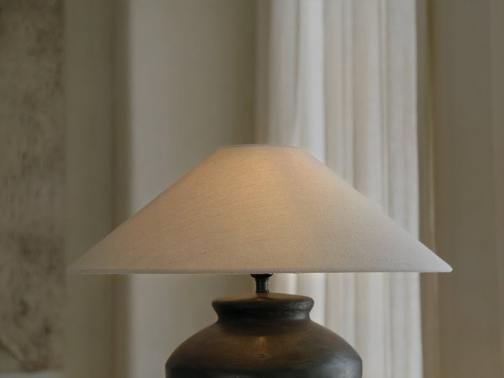Elegant white lampshade on dark vase lamp with sheer curtains background