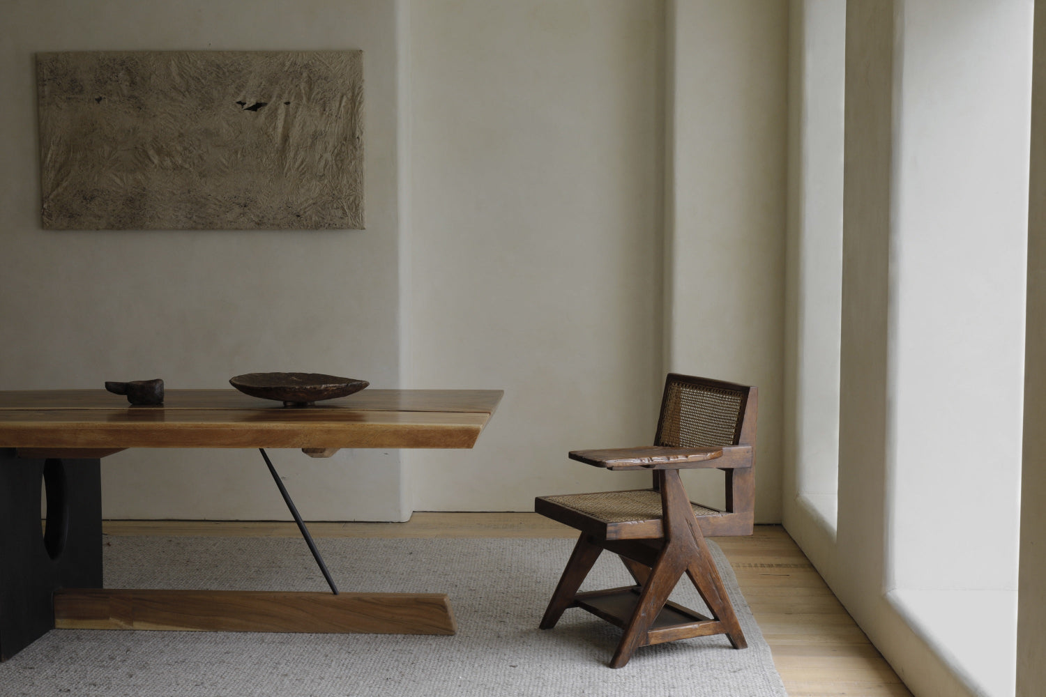 Minimalist room with a wooden desk, ZMhome’s Chandigarh Student Chair featuring a woven seat and comfortable height, neutral wall-mounted artwork, and large windows letting in natural light.