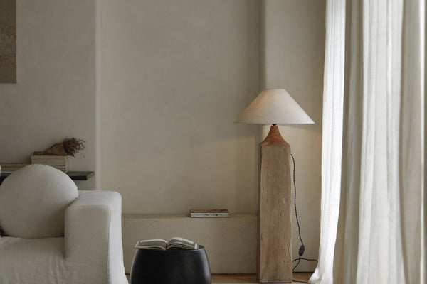 Wooden floor lamp beside a sofa in a light, airy living room