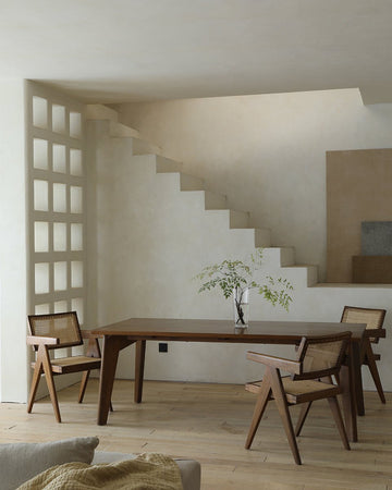 Easy Dining Table made of African teak with minimalist cane chairs in modern setting.