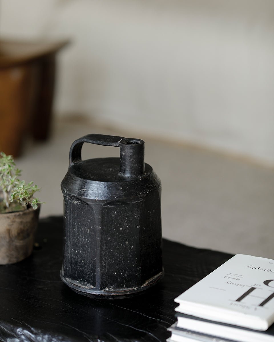 Black ceramic vase with handle, geometric design, perfect for home decor, on a dark wooden surface