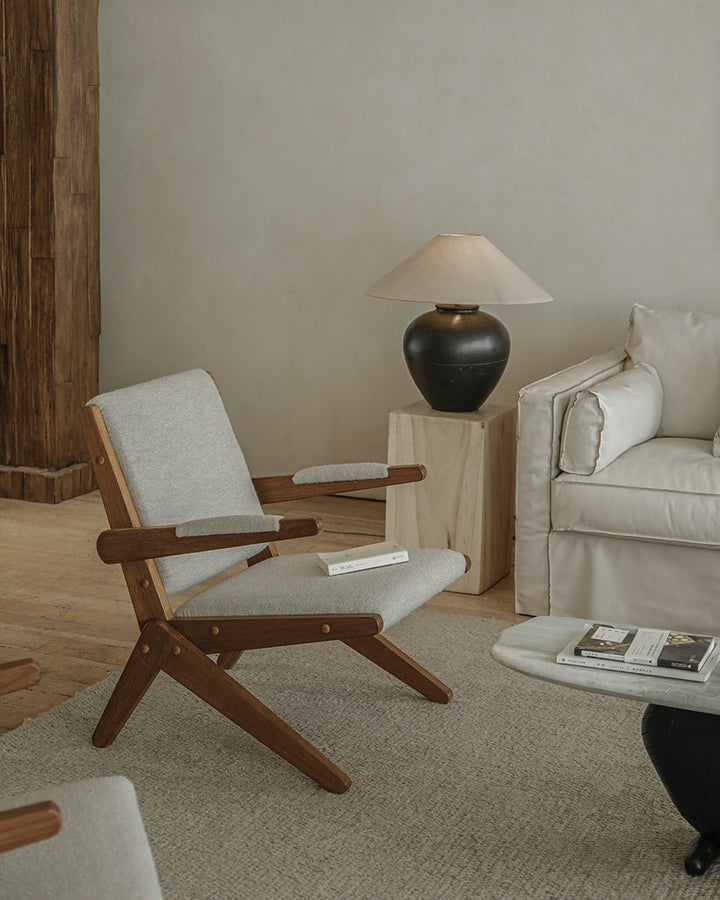 Scissors Chair in light upholstery with wooden frame, set in a modern living room.