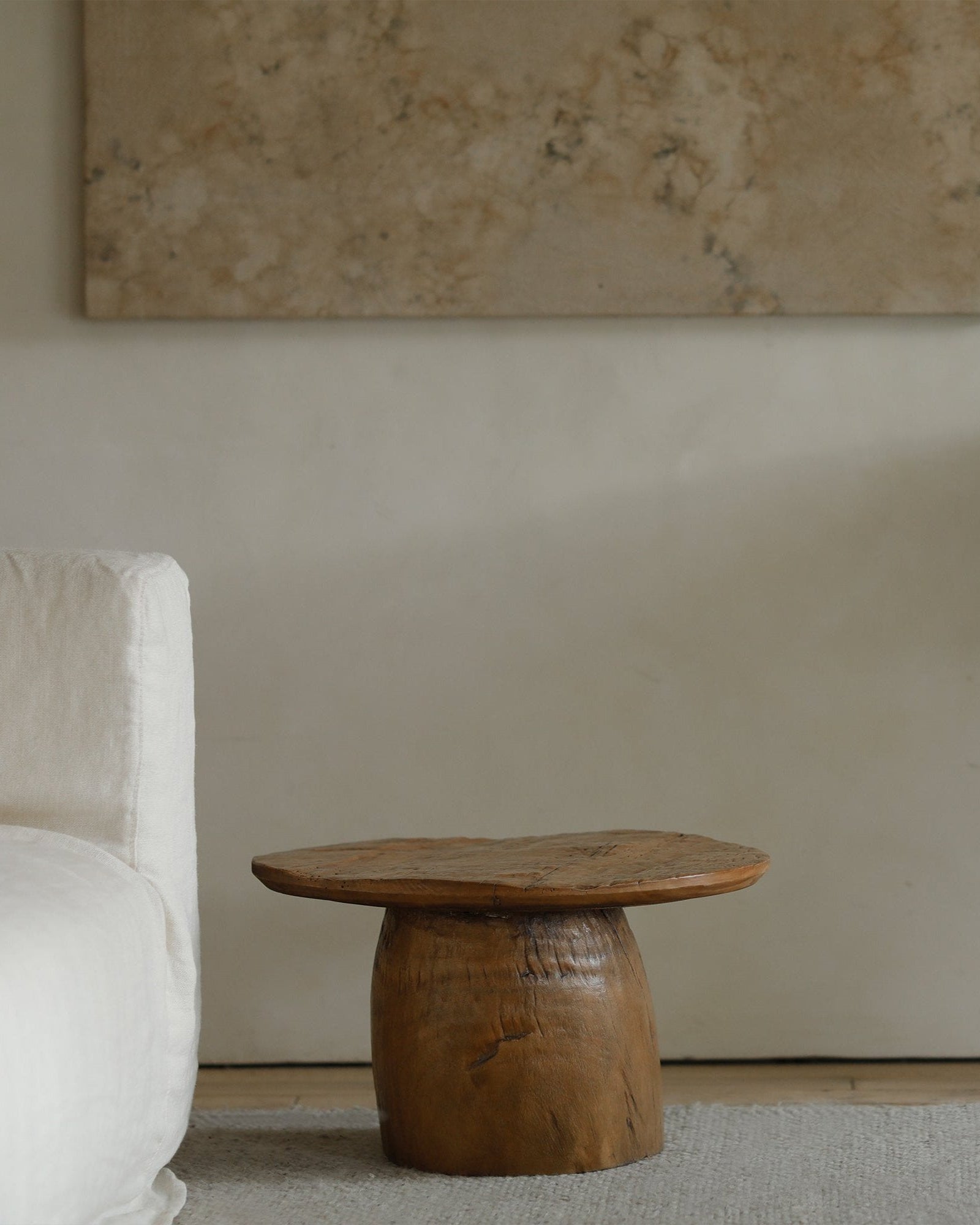 Alva Side Table in natural wood, featuring a unique distorted base and curved surfaces.