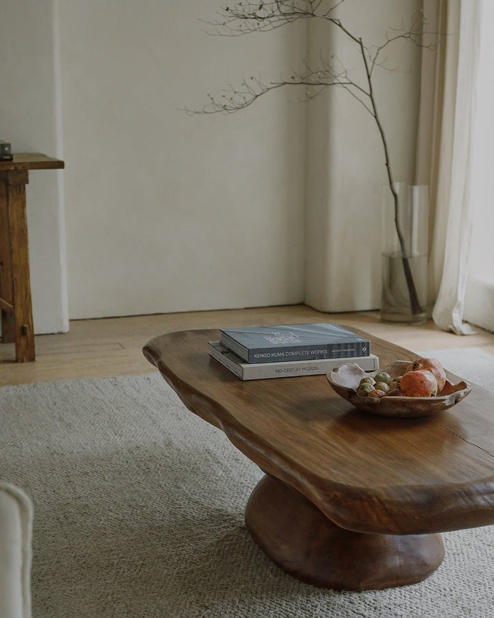Rustic coffee table topped with books and decorative bowl in a minimalist living room.