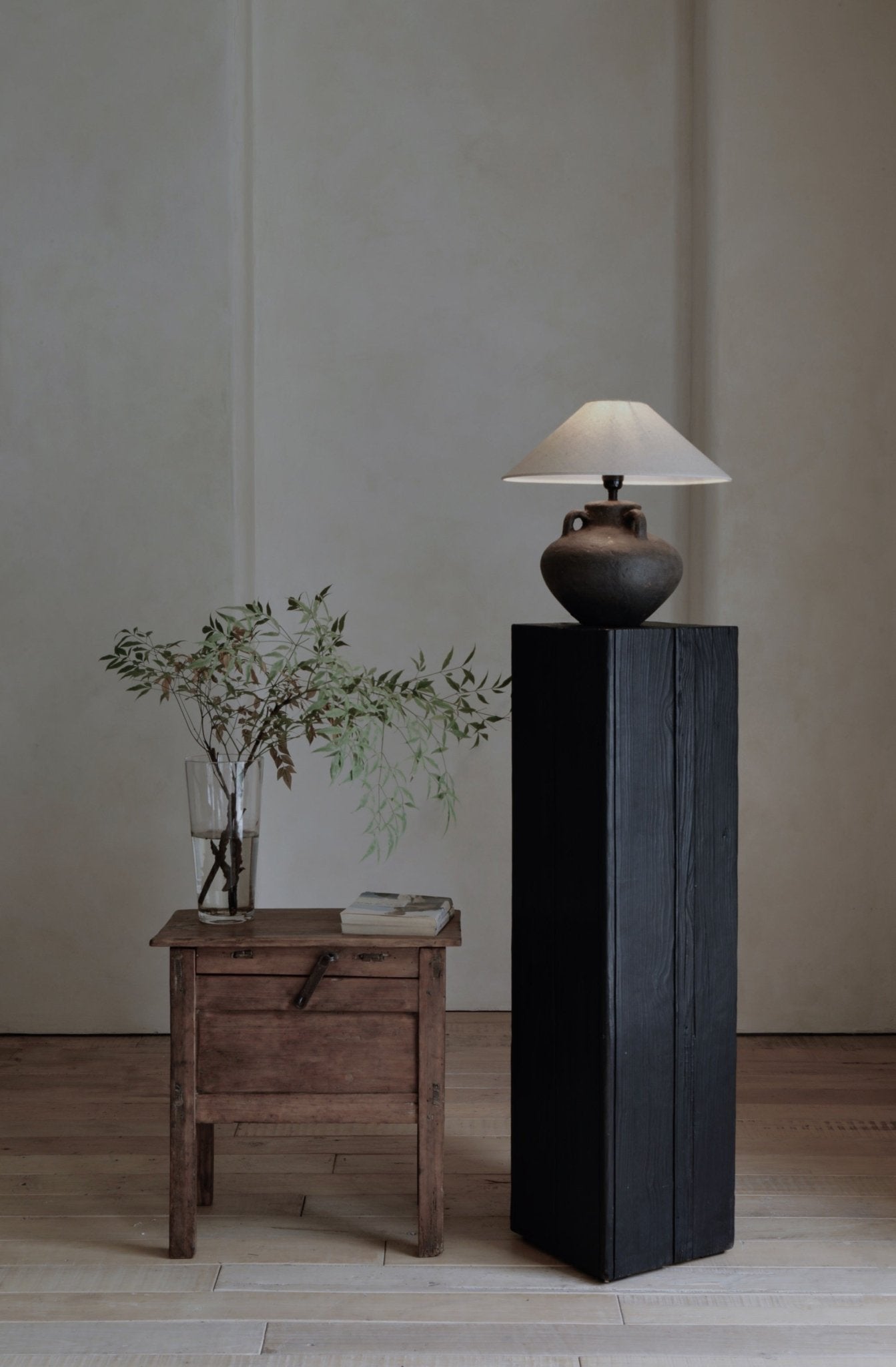 Ear Lamp with clay base and white shade on black wooden pedestal, home decor