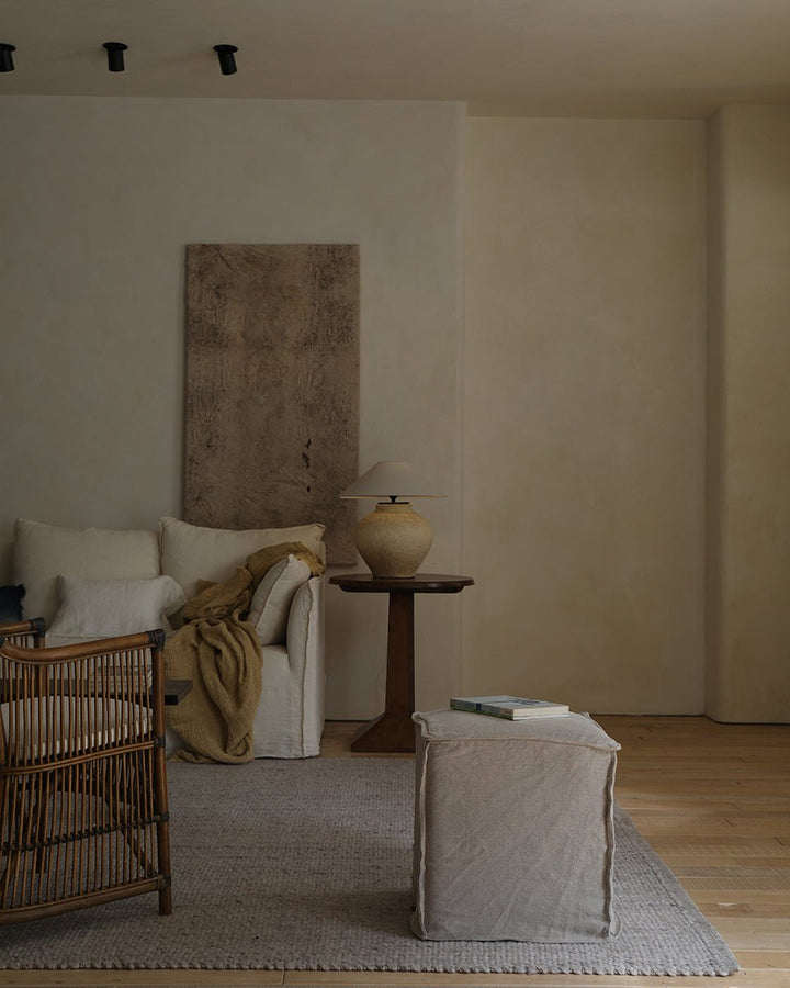 Linen cube ottoman beside handwoven chair and recliner sofa in stylish vintage living room