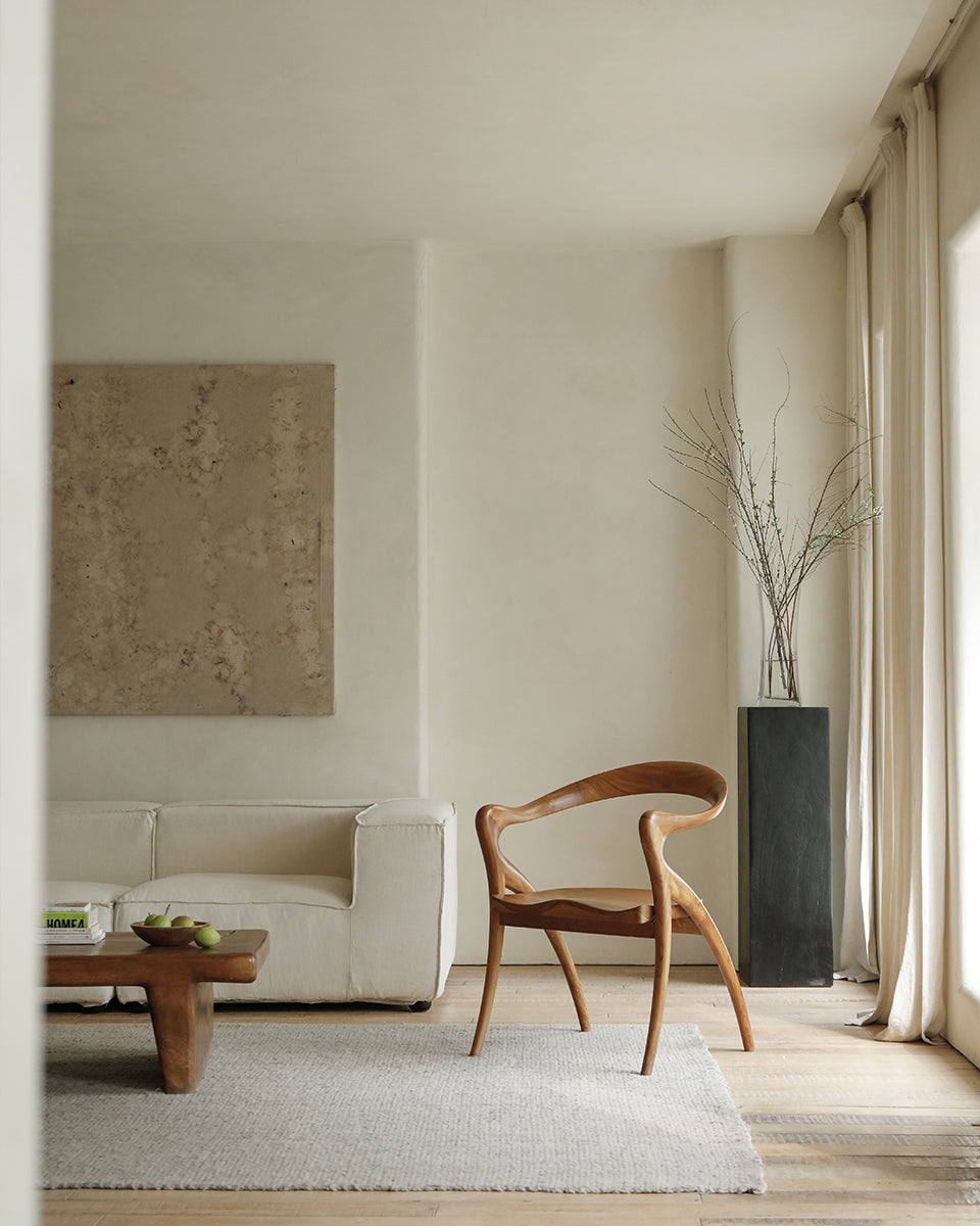 Olivia Chair in a modern interior setting. Solid teak wood, curved back, contoured seat, modern design.
