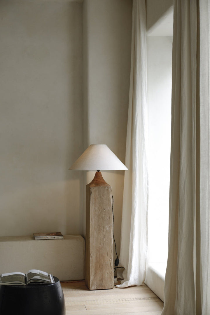 Rustic wooden floor lamp with conical shade in a serene, light-filled space