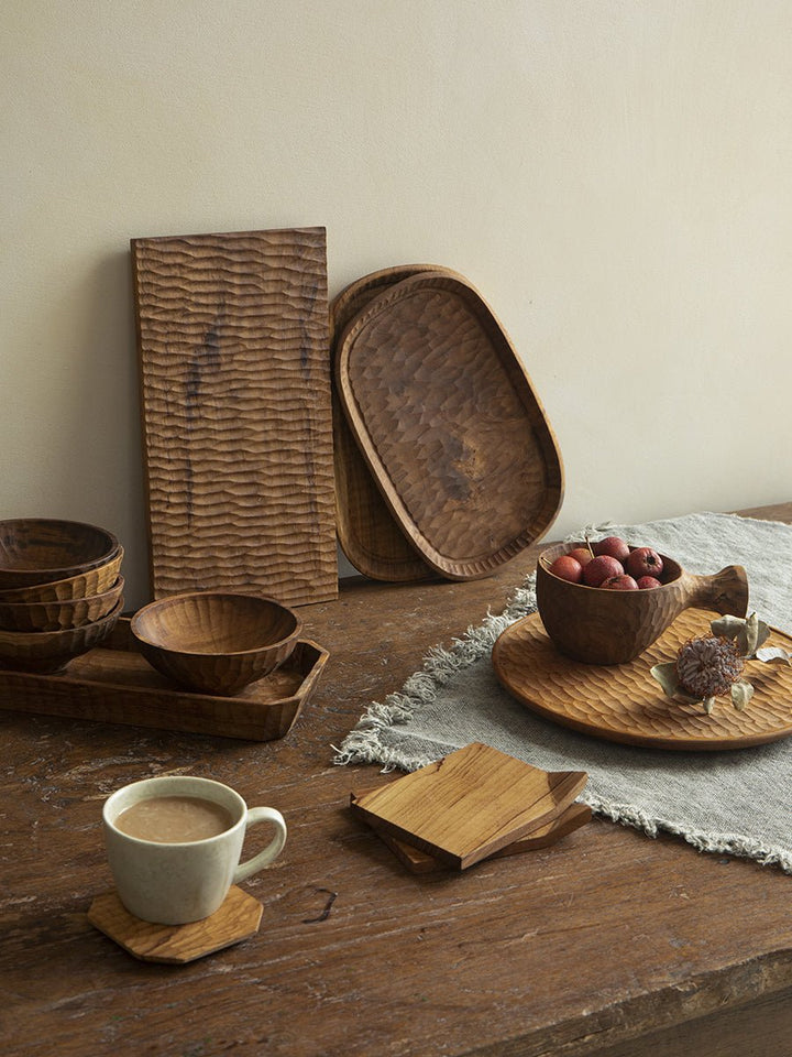 Handcrafted teak wood serving trays on a rustic table with a cup.