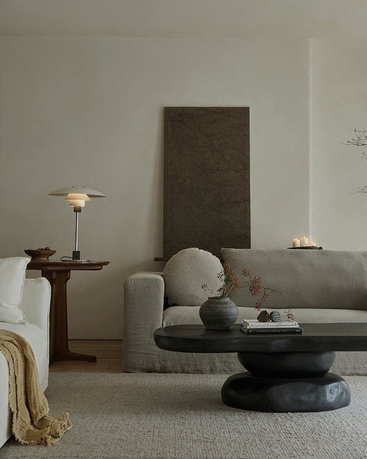 Minimalist living room with white sofa and unique round black coffee table.