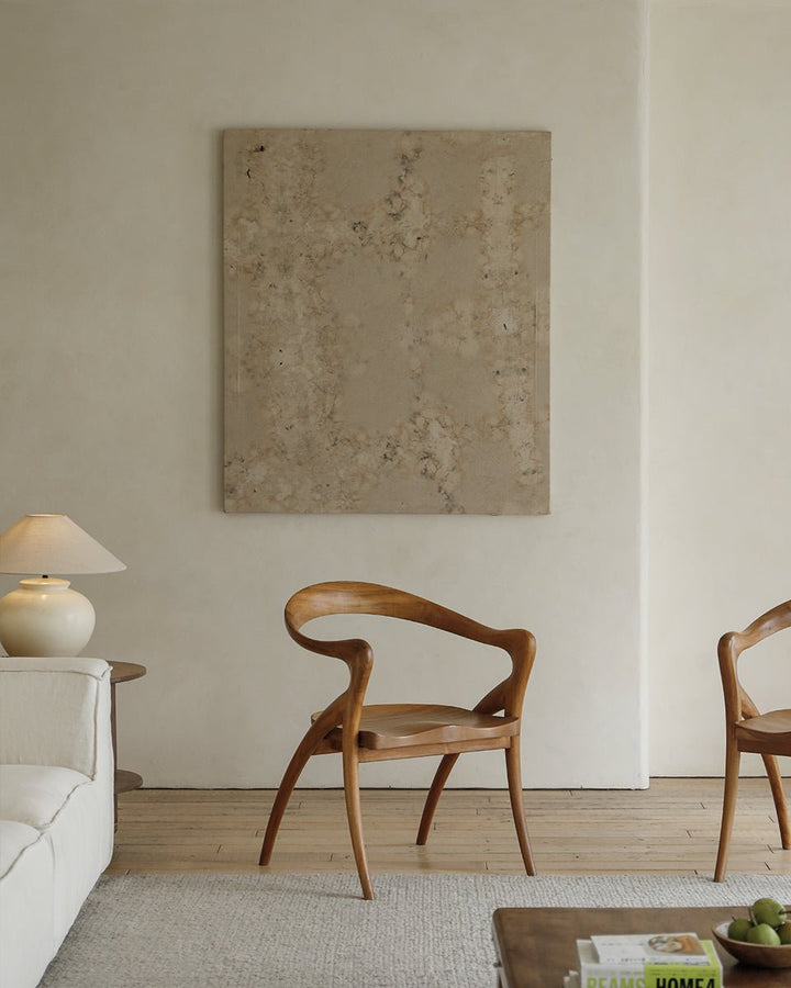 Olivia Chairs in a minimalist living room with warm lighting and a beige wall art.