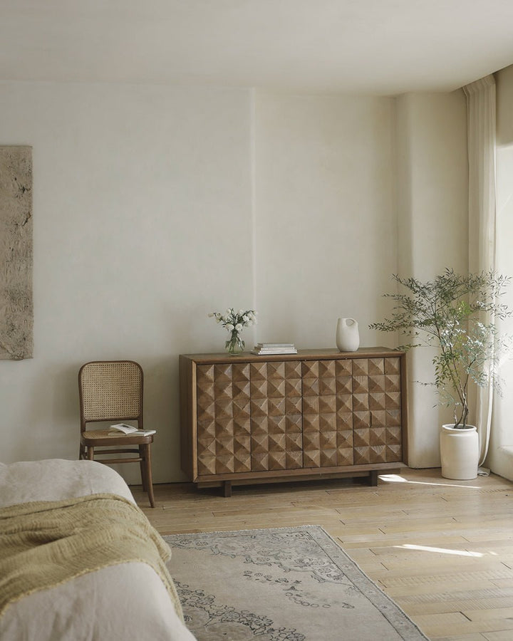 Bumpy sideboard with geometric design in bright living room decor, vase on top.
