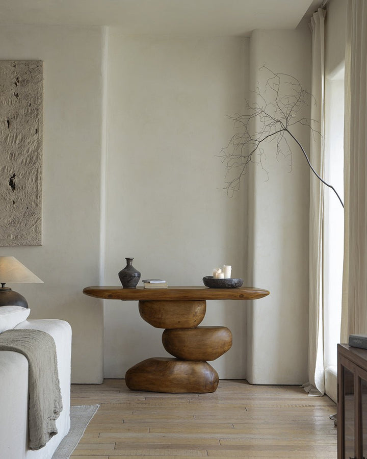 Modern console table with a rounded wooden top and sculptural base in neutral decor.