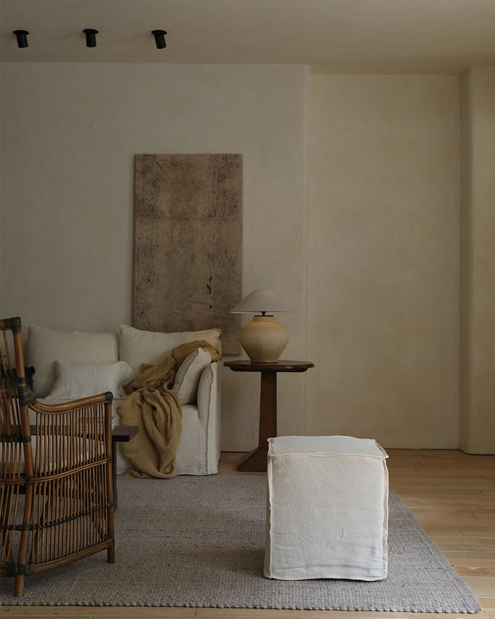 Linen cube ottoman in a serene vintage living room with earthy textures.