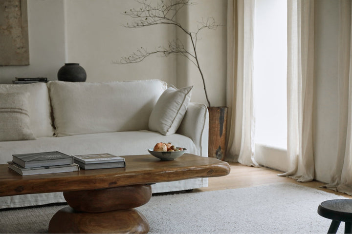Minimalist living room with white sofa and unique wood coffee table styled with fruit.