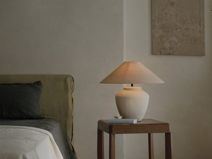 Cozy minimalist bedroom with white lamp, green bed, and wooden side table decor