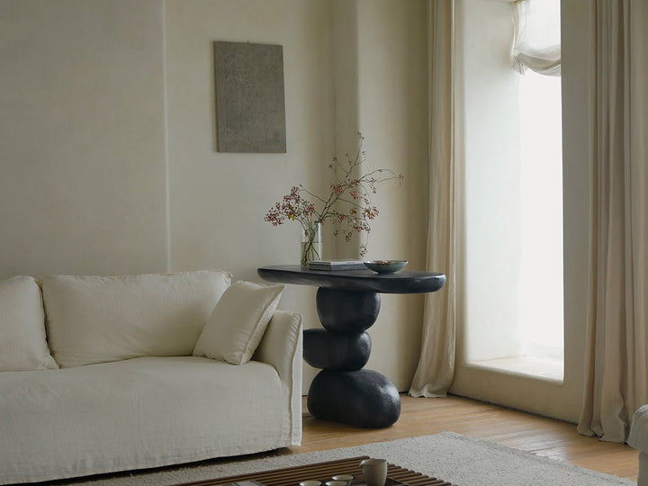 Modern black console table with organic curves in a minimalist living room.