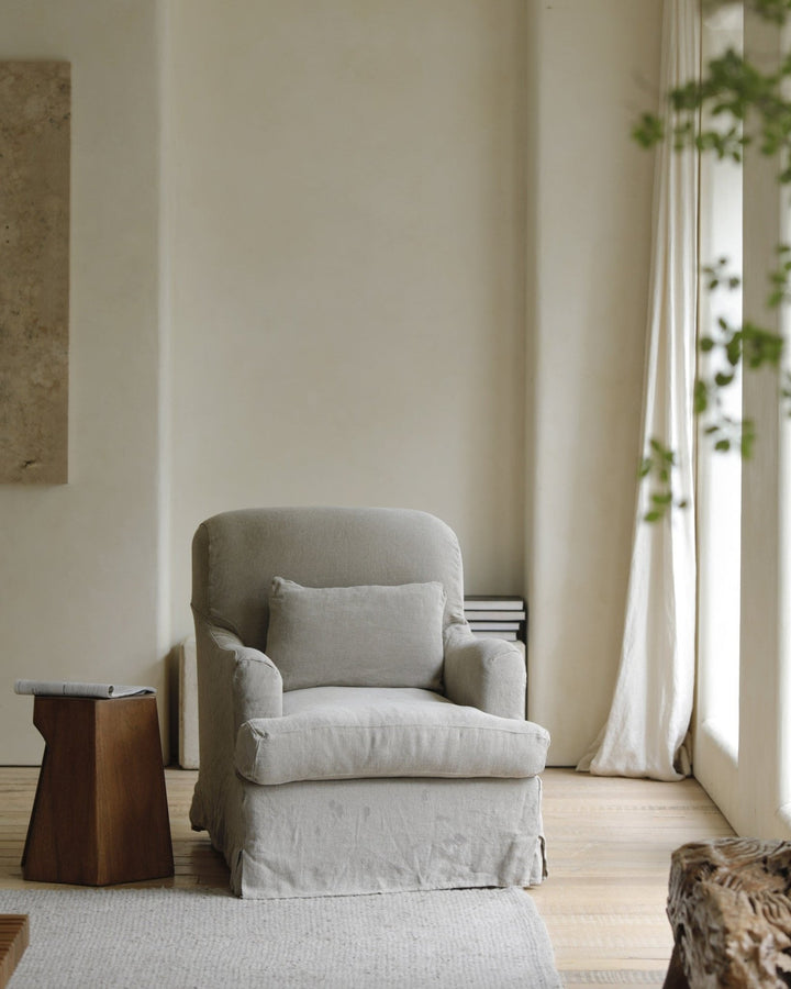 Gray slipcover armchair with plush cushion in a cozy, neutral-toned living room